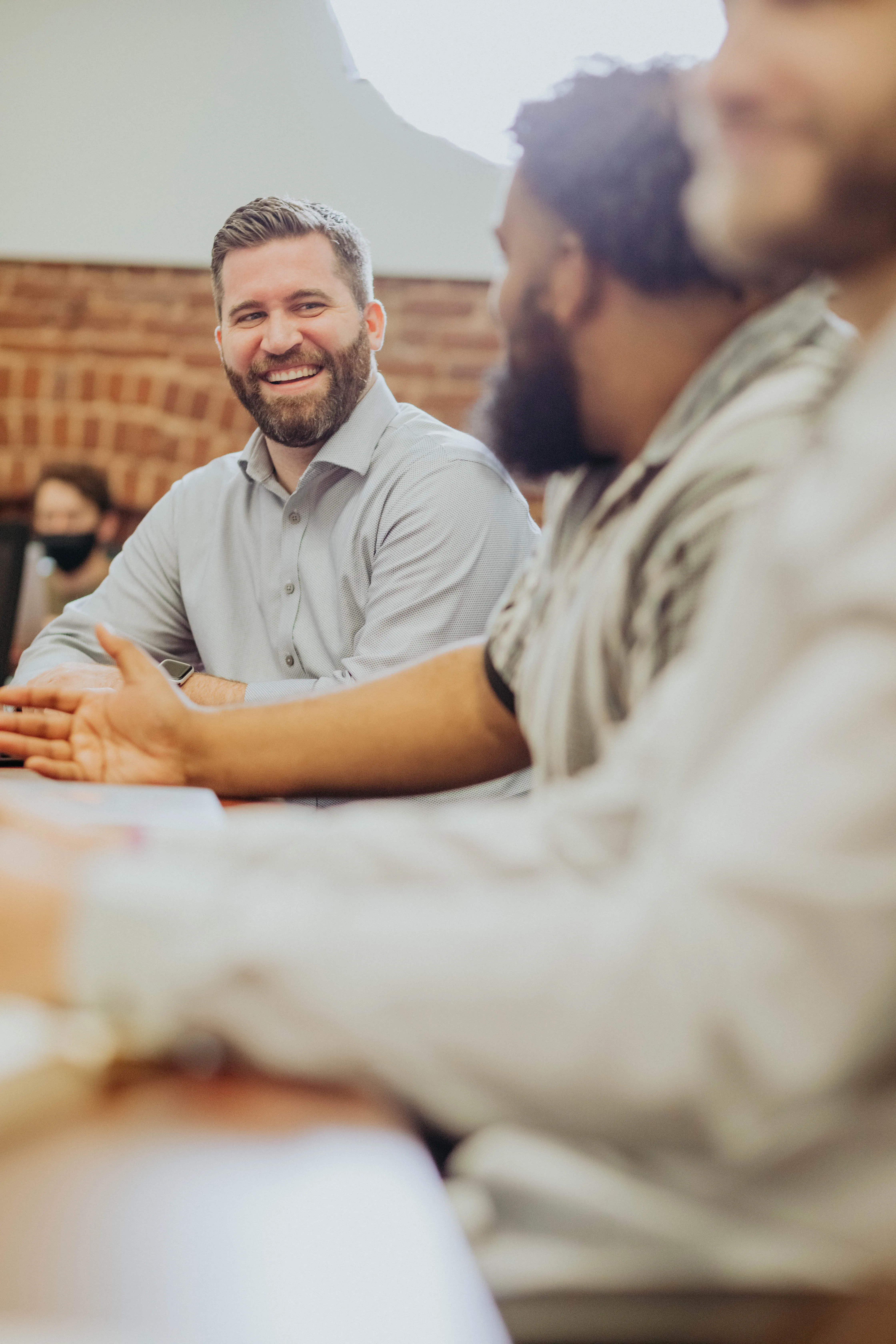 Two men face each other laughing at a conference table.